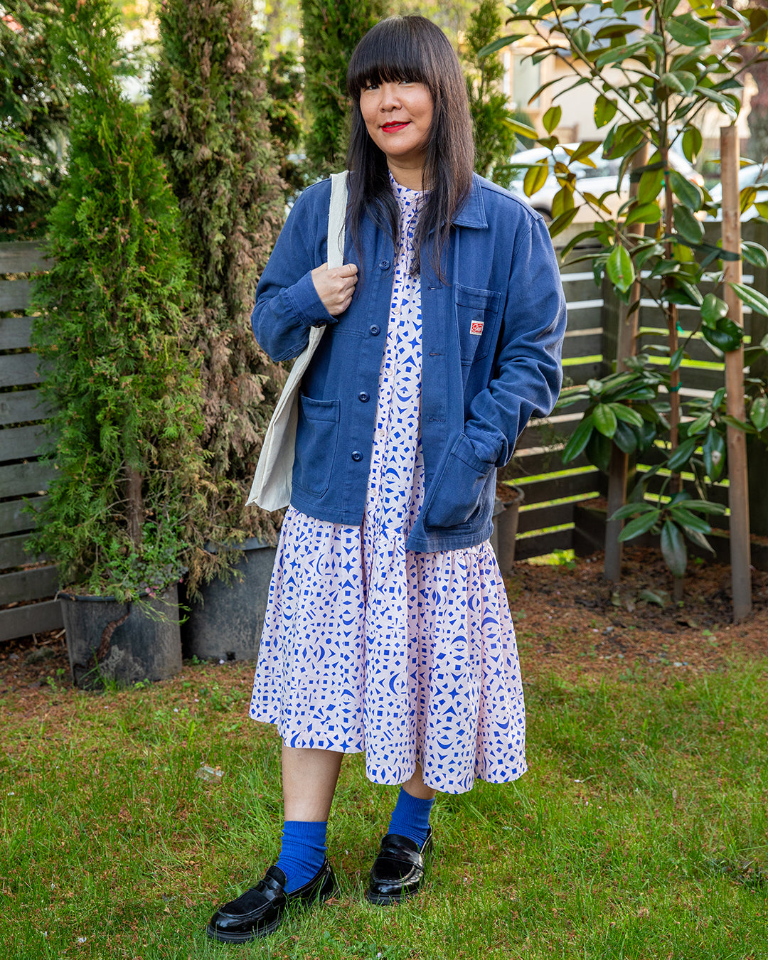 Woman wearing a blue jacket soft peach dress with cobalt blue snowflake pattern on it