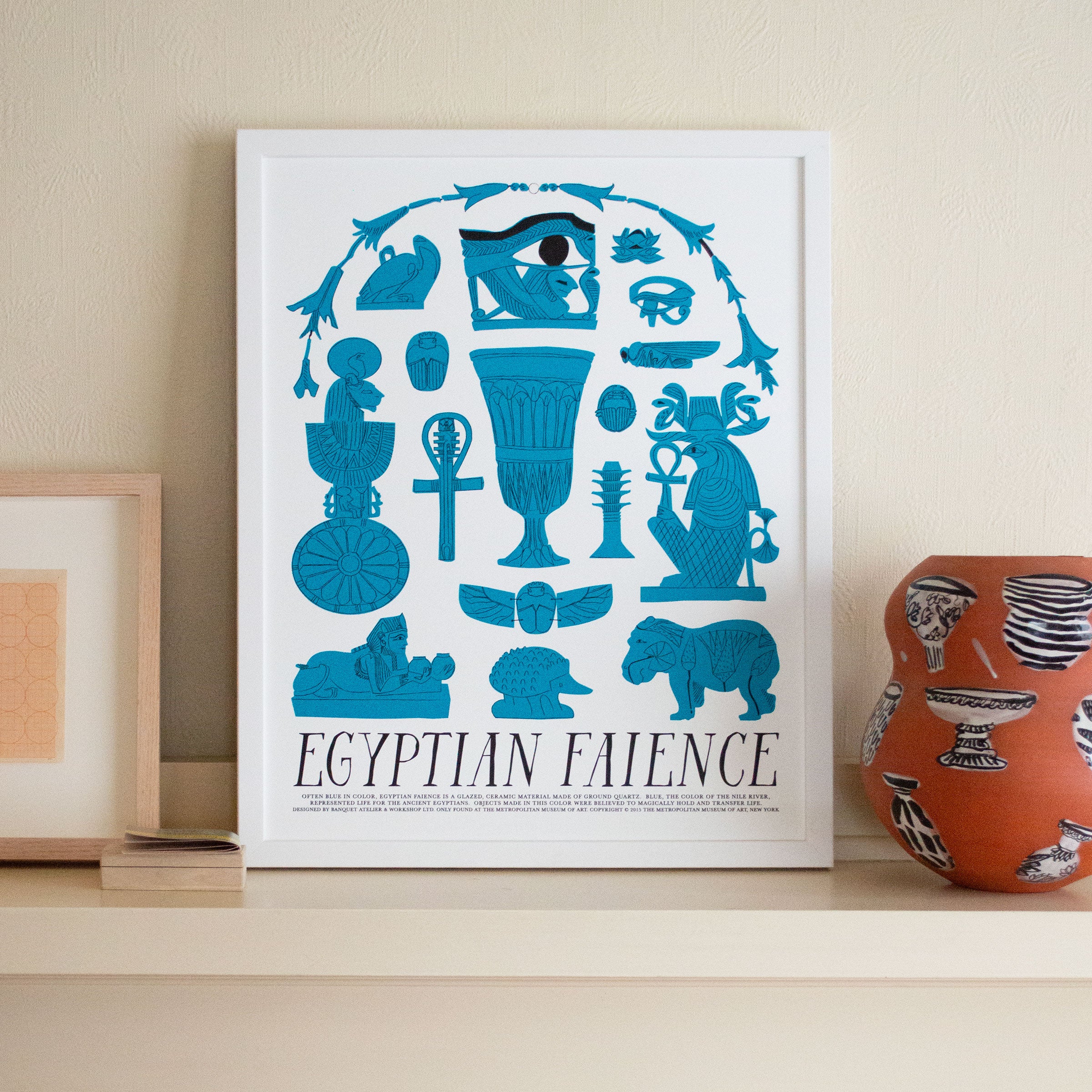 art print with black text Egyptian Faience and Egyptian imagery in bright turquoise on shelf with clay pot and frames art