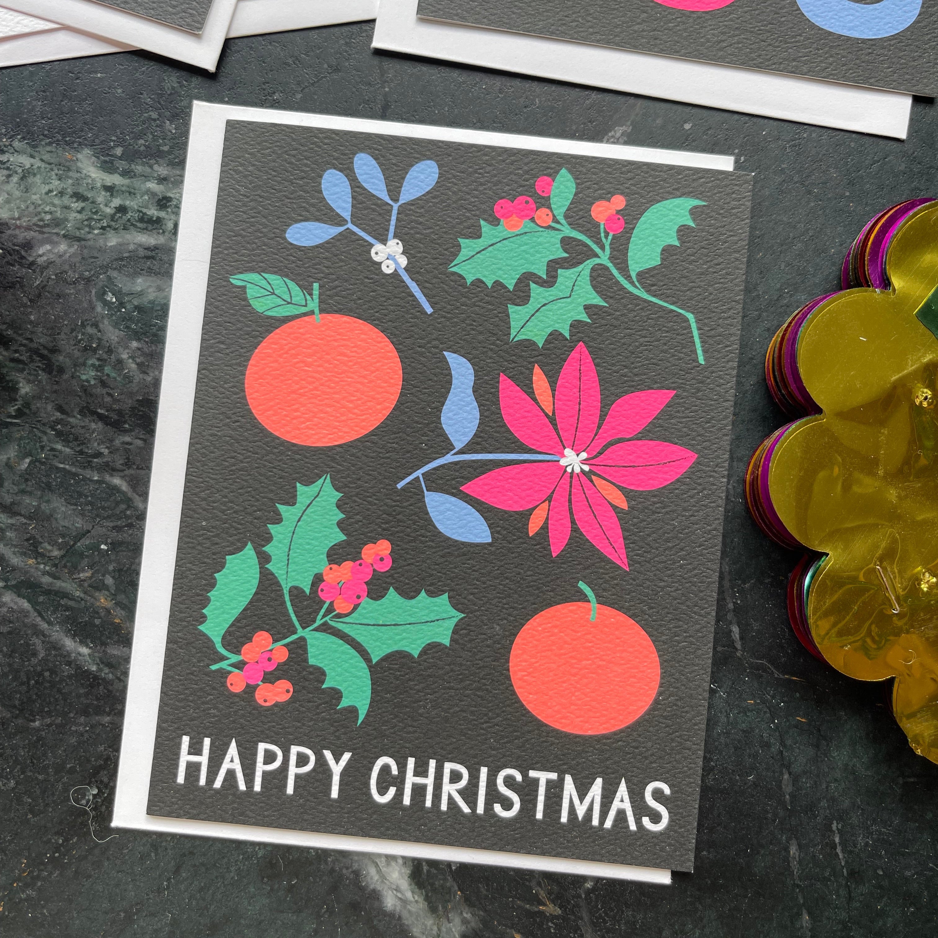 Christmas card with floral designs and 'Happy Christmas' text on a dark surface