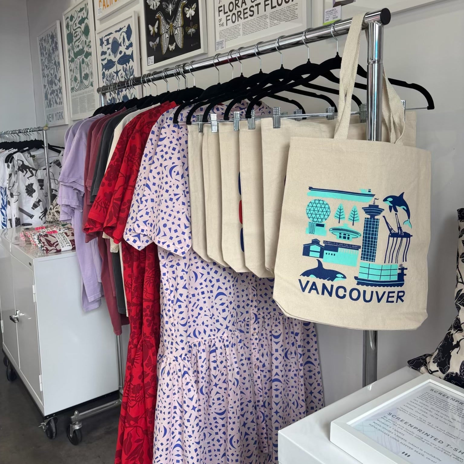Stack of tote bags with a Vancouver design on a rack at Banquet Workshop's Granville Island studio.