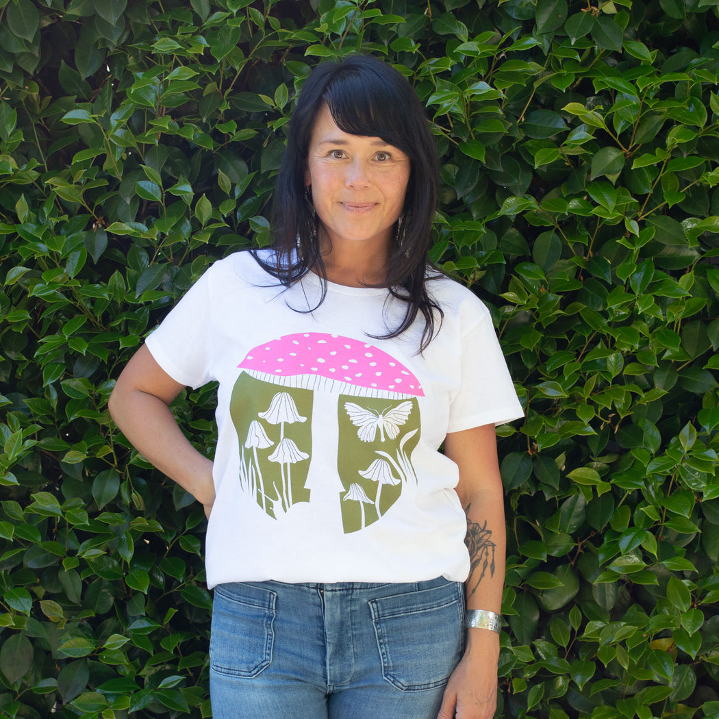 beautiful woman wearing a white t-shirt printed with neon pink and khaki mushrooms, a moth and a snail