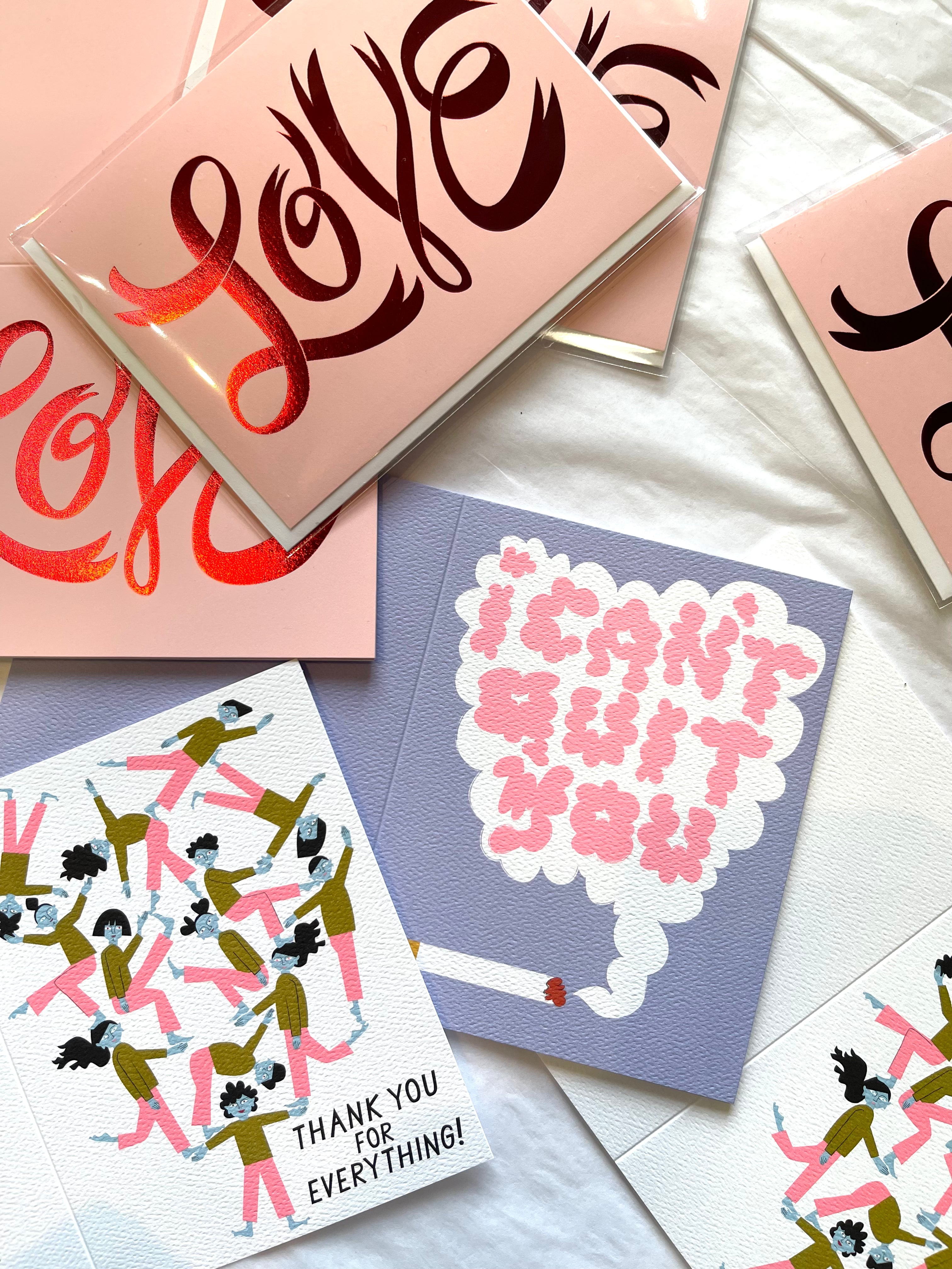 Note card with a pile up of cute blue faced humans with one person holding them up with text that said Thank You For Everything with another card with red foil text that says LOVE on it in a hand drawn font and another card with a cigarette with a cloud of smoke that states I Can't Quit YOu