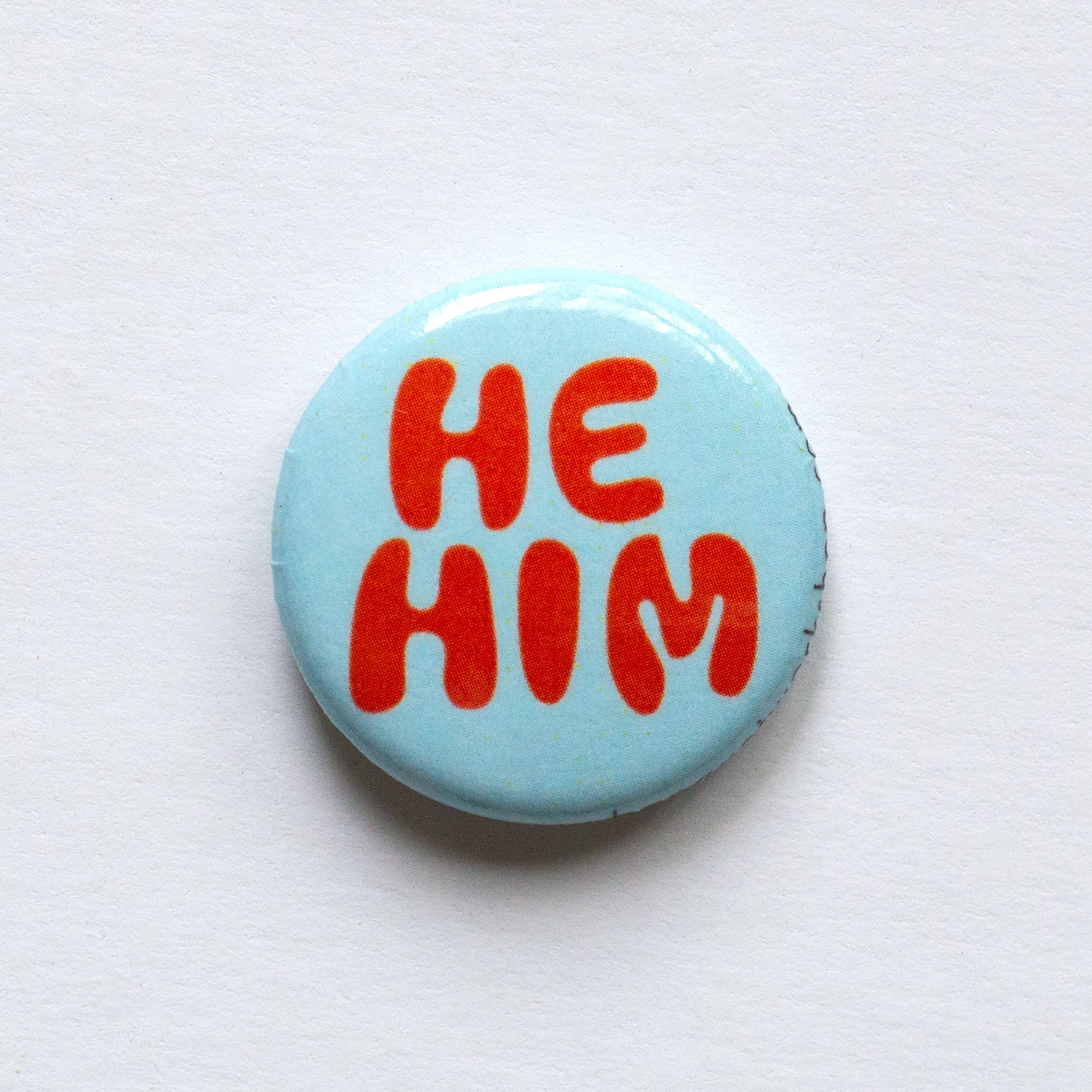 red and turquoise he him 1 inch button