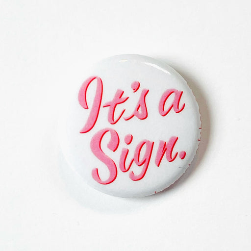 It's a Sign button in pink cursive on a 1" button