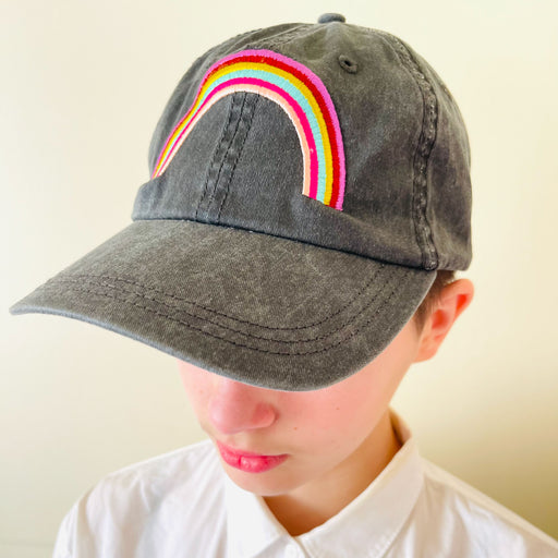 woman wearing a dark grey stonewashed cotton ball cap embroidered with a vibrant rainbow