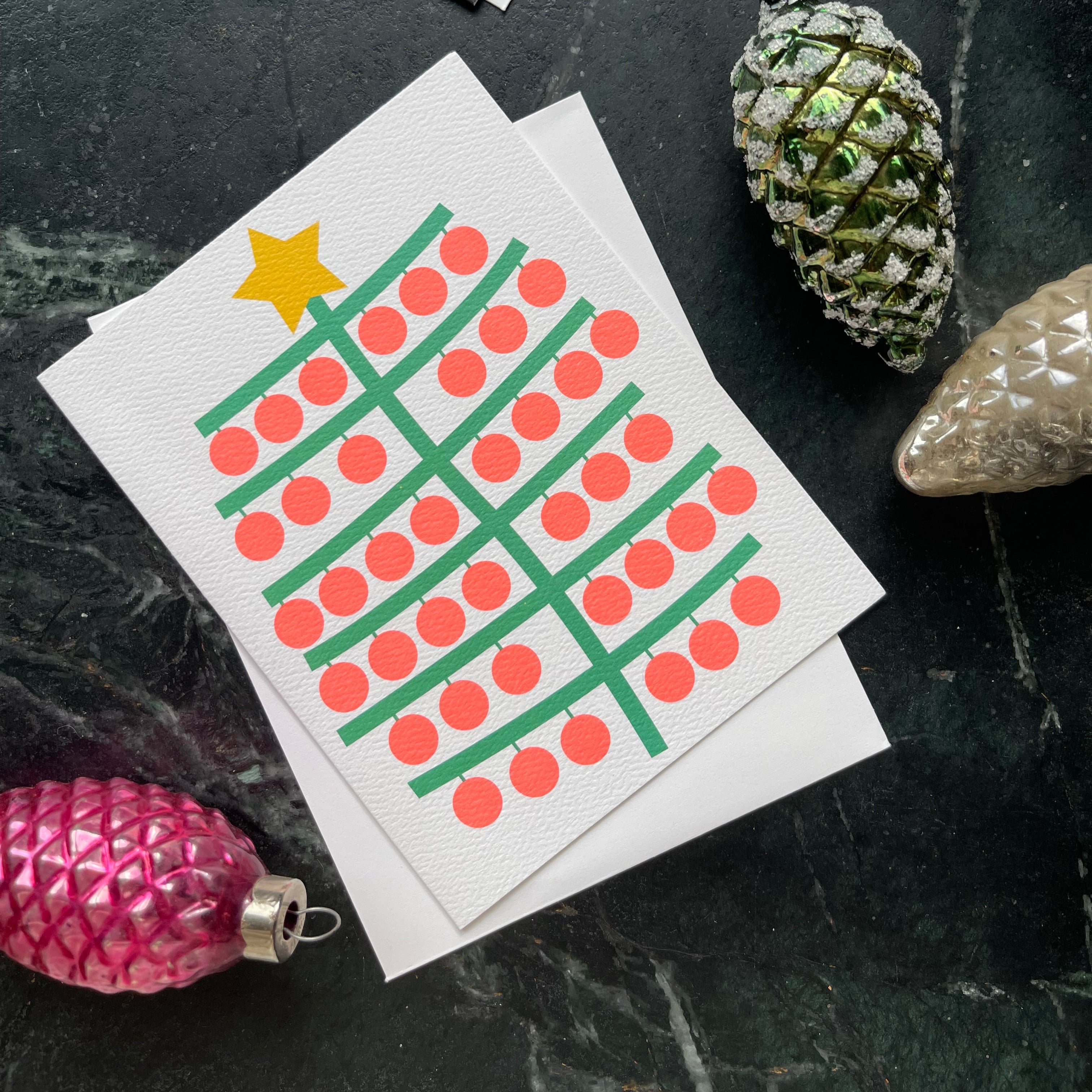 holiday card with a simplified tree with neon orange bobbles